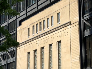 Toronto Menkul Kıymetler Borsası binasının dış kısmında sanat deco taş işçiliği, simetrik pencereler ve ana girişin üzerine oyulmuş kurum adı yer almaktadır - Toronto, Kanada - 22 Haziran 2025