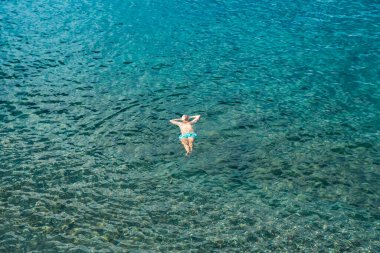 Dominica, Roseau - 12 Kasım 2022: Açık tropik sularda yüzen ve yaz tatilinin tadını çıkaran bir adamın üst görüntüsü