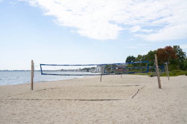 Empty beach with volleyball nets set up for playing. Houses along the shore in Connecticut