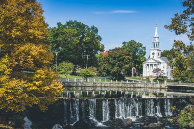 Milford, town in Connecticut. View of white church and waterfall surrounded by trees