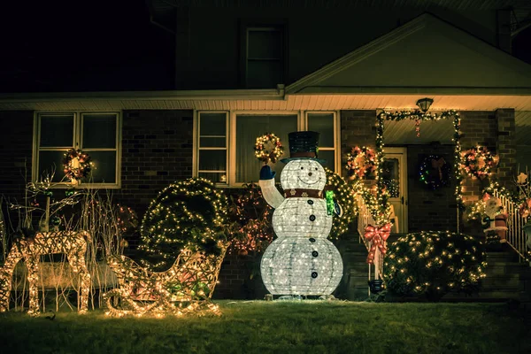 Christmas decorations glowing outside at night in front of a house. Christmas lights