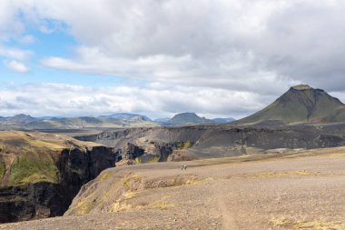 Hikers exploring beautiful Icelandic landscape. Walking through vast land of Iceland with canyon