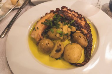 Restoranda servis edilen beyaz uçakta fırında patates ve zeytinyağıyla ızgara ahtapot.