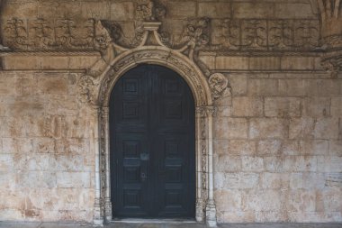 Dekoratif çerçeve ve taş duvarlı siyah ahşap kapılar