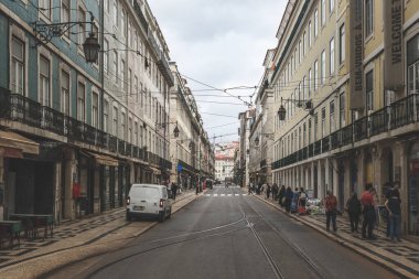 Lizbon, Portekiz - 8 Mart 2023: Lizbon, Portekiz 'de dar, tepelik kaldırım taşı caddesi ve yan tarafındaki apartmanlar