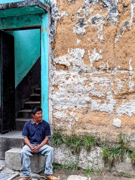 Chichicastenango, Guatemala - 22 Mayıs 2023: Endişeli adam açık bir binanın yanındaki bir taşın üzerinde oturuyor