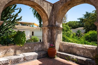 Güneşli bir yaz gününde açıkta görünen, palmiye ağaçları ve binalı taş kemerler.