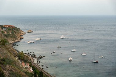 Taormina, Sicilya 'daki tepeden denize ve tren istasyonlu uçurumlara bakın.