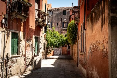 Venedik 'te saksı bitkileri olan binalar. Panjurlarla büyüleyici bir görünüş. Asfalt kaldırım