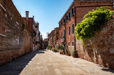 Venedik 'te saksı bitkileri olan binalar. Panjurlarla büyüleyici bir görünüş. Asfalt kaldırım
