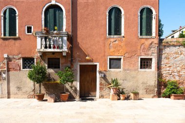 Venedik 'te saksı bitkileri olan binalar. Panjurlarla büyüleyici bir görünüş. Asfalt kaldırım