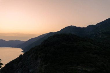 İtalya sahillerinde gün batımı. Silüet dağları ve denizle akşam