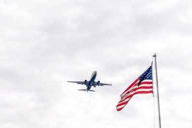Delta Havayollarından gelen uçak arka planda Amerikan bayrağına karşı gökyüzünde uçuyor.