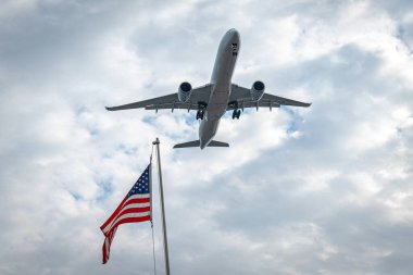 Uçak Airbus A350 Amerikan bayrağının arka planında gökyüzünde dalgalanıyor.