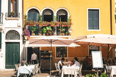 Venedik, İtalya - 14 Ağustos 2023: Venedik, İtalya 'da küçük bir meydanda restoran masaları ve sandalyeleri