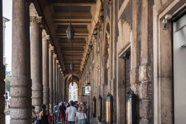 Verona, İtalya - 16 Ağustos 2023: Dışarıdaki insanlarla birlikte taş sütunlardan oluşan uzun geçitlerin görüntüsü azalıyor