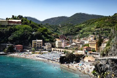 Monterosso, İtalya - 10 Temmuz 2023: Cinque Terre, İtalya 'daki köylerden biri olan Monterosso' nun güzel manzarası. Renkli binaların yanında turistlerin olduğu plaj