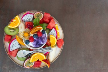 Karışık meyveli renkli tabaklar ve masada yoğurtlu küçük kâse.