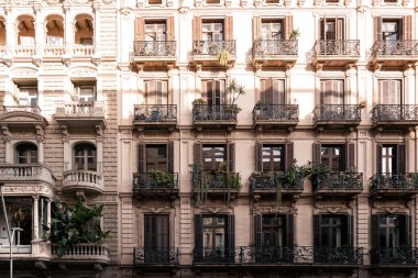 Balkonlarda panjurları ve bitkileri olan tarihi binanın ön cephesi.