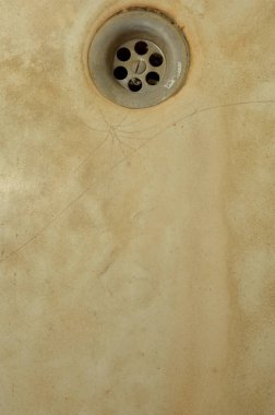 Eski bir küvetin arka planında metal bir lavabo var.