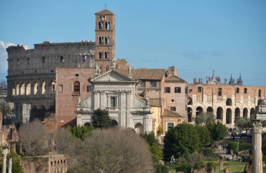 Görkemli mimari, ünlü kolezyum ve tarihi yapıların yer aldığı Roma manzarasını doldurur. Ziyaretçiler güneşli bir günde bu antik mekanlara hayran kalırlar..