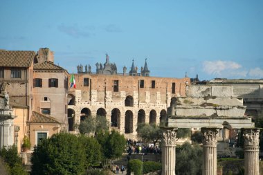 Görkemli mimari, ünlü kolezyum ve tarihi yapıların yer aldığı Roma manzarasını doldurur. Ziyaretçiler güneşli bir günde bu antik mekanlara hayran kalırlar..