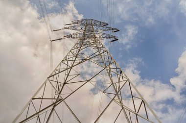 Looking up at a High Voltage Electric Tower with a cloudy blue sky