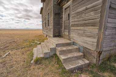 Saskatchewan, Kanada 'da terk edilmiş bir çiftlik evinin kapısına ve basamaklarına bakıyorum.