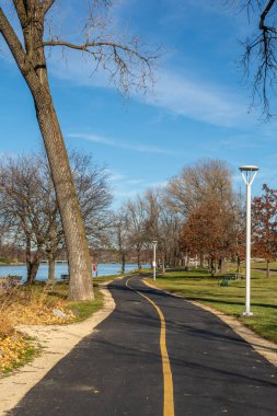 Güneşli bir sonbahar gününde bisiklet yolu ve nehir boyunca yürüyüş yolu. Rockford, Illinois, ABD.