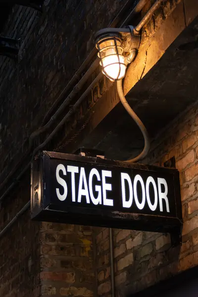Vintage illuminated stage door sign in a dark and dingy back alley in the city of Chicago, Illinois, USA