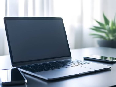 Bir dizüstü bilgisayar ve akıllı telefonun minimalist yakın çekimi, temiz ve modern bir çalışma alanı sergiliyor. Teknoloji ve üretkenlik temaları için ideal.