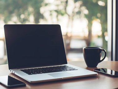 Dizüstü bilgisayar, akıllı telefon ve kahve fincanı sergilenecek, modern bir çalışma alanı için mükemmel. Üretkenlik ve basitlik temaları için ideal.