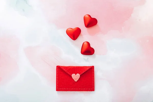 色の背景にバレンタインデーのための赤い心を持つフェルト封筒 ストック画像
