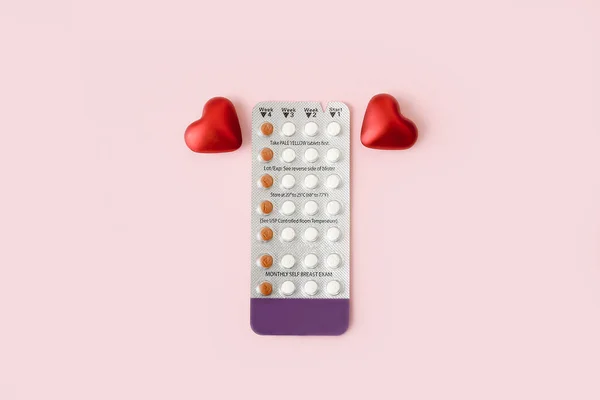 Women contraceptive hormonal birth control pills blister with red hearts on pink background