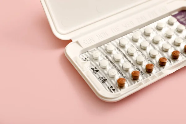 Female oral contraceptive pills blister on pink background. Women contraceptive hormonal birth control pills.