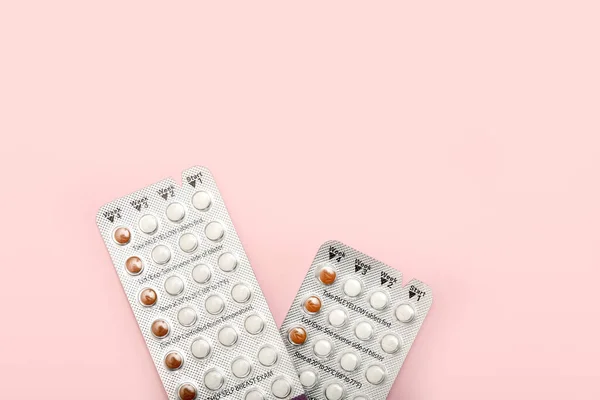 Female oral contraceptive pills blisters on pink background. Women contraceptive hormonal birth control pills.