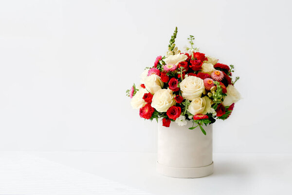 Beautiful bouquet of flowers decorated in round box on light background