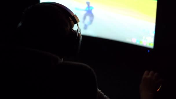 男孩玩网络游戏的专业网络游戏 坐在黑暗中的椅子上 灯光五彩斑斓 背景色 — 图库视频影像