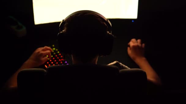 男孩玩网络游戏的专业网络游戏 坐在黑暗中的椅子上 灯光五彩斑斓 背景色 — 图库视频影像