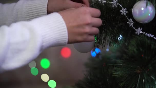 Kinderhand Weißem Pullover Schmückt Weihnachtsbaum Mit Weißer Kugel Und Dreht — Stockvideo