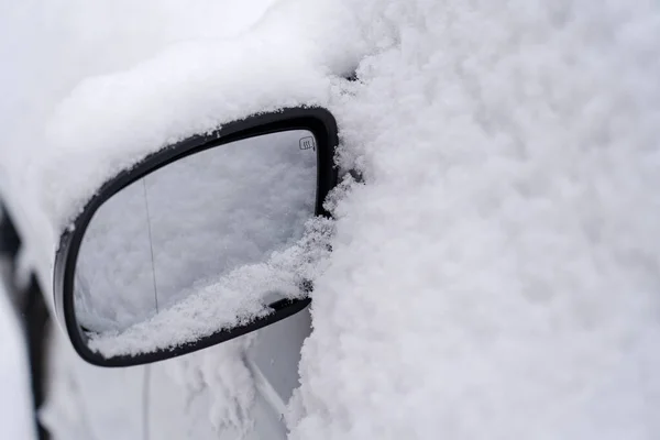 Car is covered with snow, windows and mirrors. Close-up.