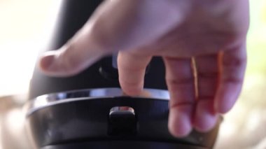 Mans hand turns on the electric kettle button. Close-up. 