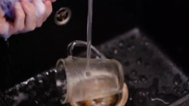 Mans hands wash clear cup of foaming detergent. Selective Focus.