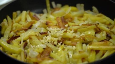 Garlic is added to homemade fried potatoes, fried potatoes are mixed. 