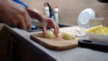 Mens hands cut a white bow with a knife on a cutting board. Focus on knife.