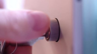 Hand opens lock on door with key, twists in both directions, macro shooting, close-up.