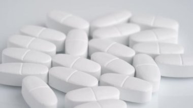 White oblong tablets with a dividing strip rotate macro. 