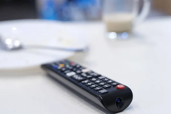 TV kumandası masada, mutfakta boş bir tabak ve fincanın yanında, kahvaltı bitti.. 