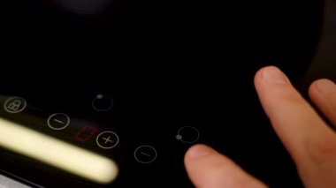 Mens fingers turn on electric stove and raise temperature. 