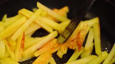 Fried golden potatoes with crust are fried in oil and turned over with spatula. 
